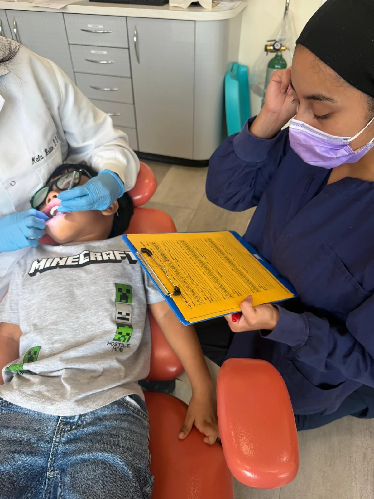 Young patient holding an activity clipboard during a dental checkup