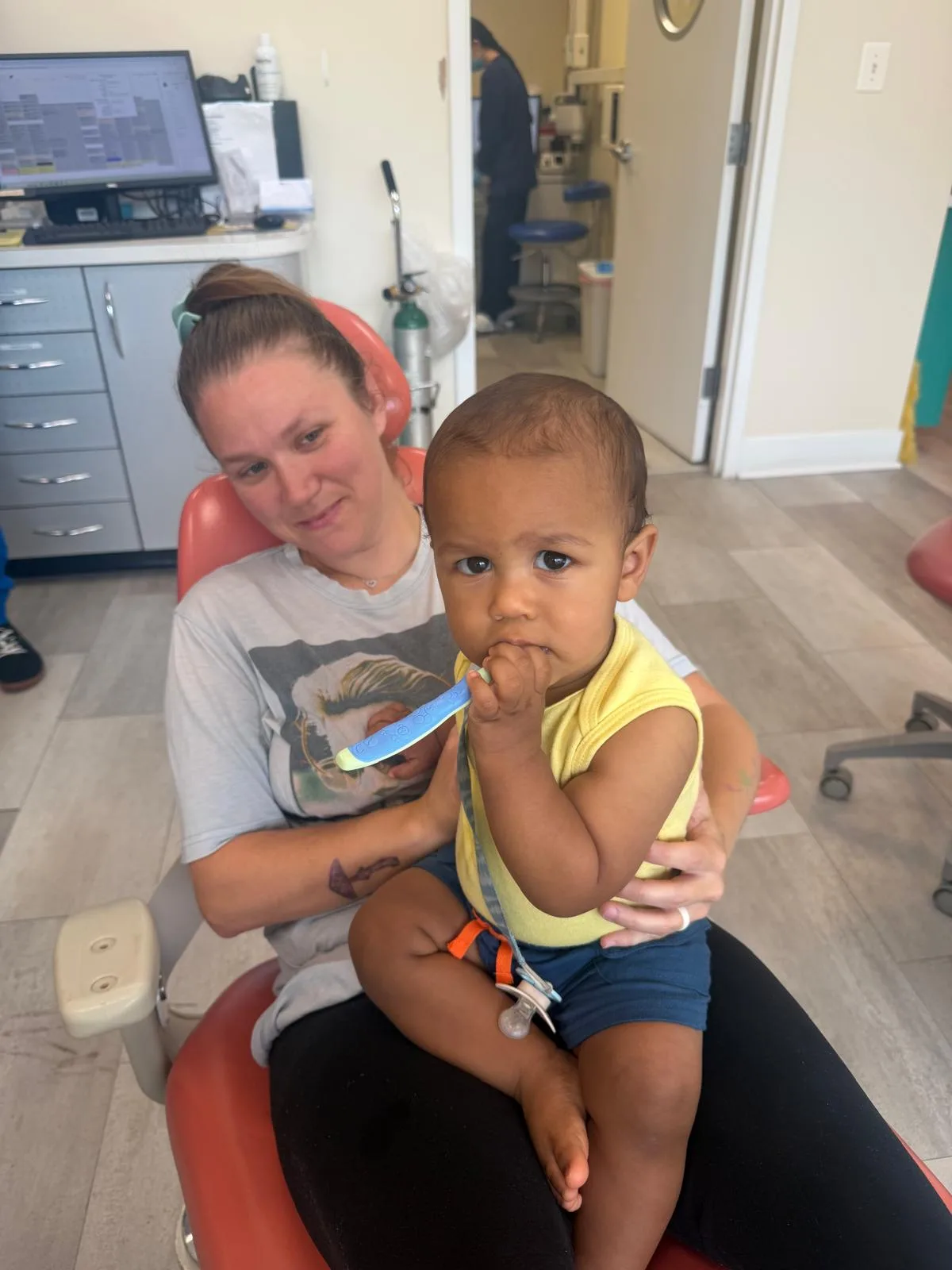 Pediatric dental team member comforting a toddler during his first dental visit