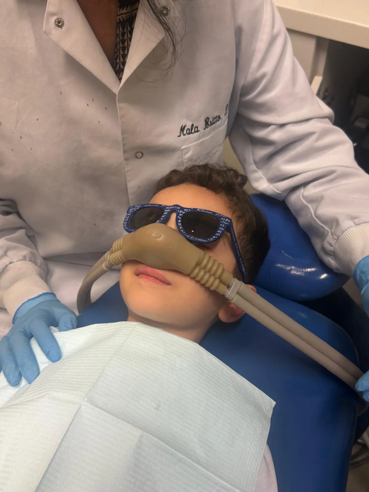 Young patient wearing a nitrous oxide nasal hood during treatment