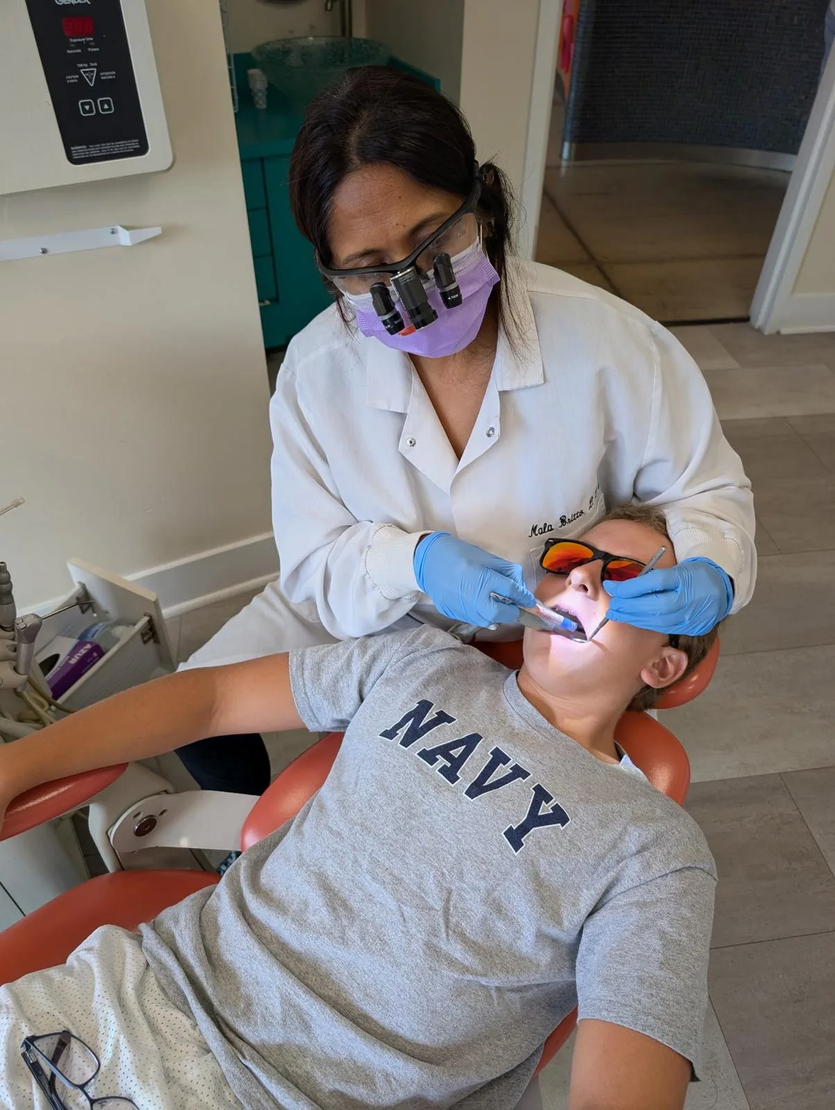Dental hygienist cleaning a young patient's teeth at a recall appointment